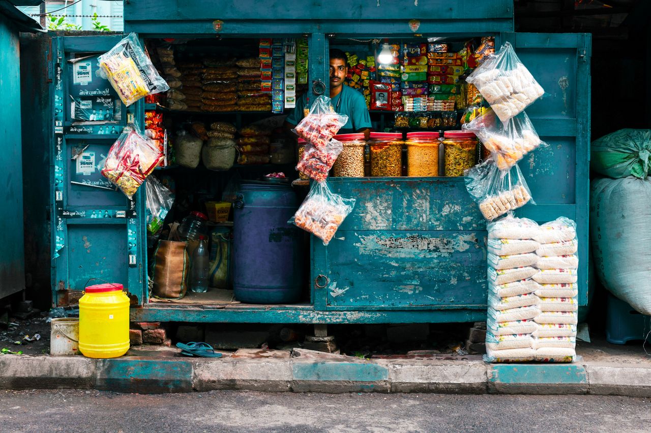 about-us A vibrant street vendor stall in Kolkata selling snacks and essentials.